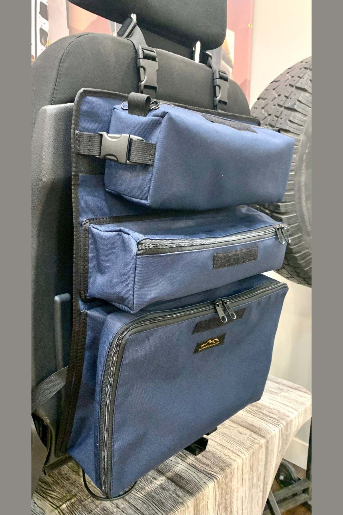 Arches Overlander 1 Seat Organizer attached to vehicle seat, showcasing spacious blue storage pockets for organizing essentials.