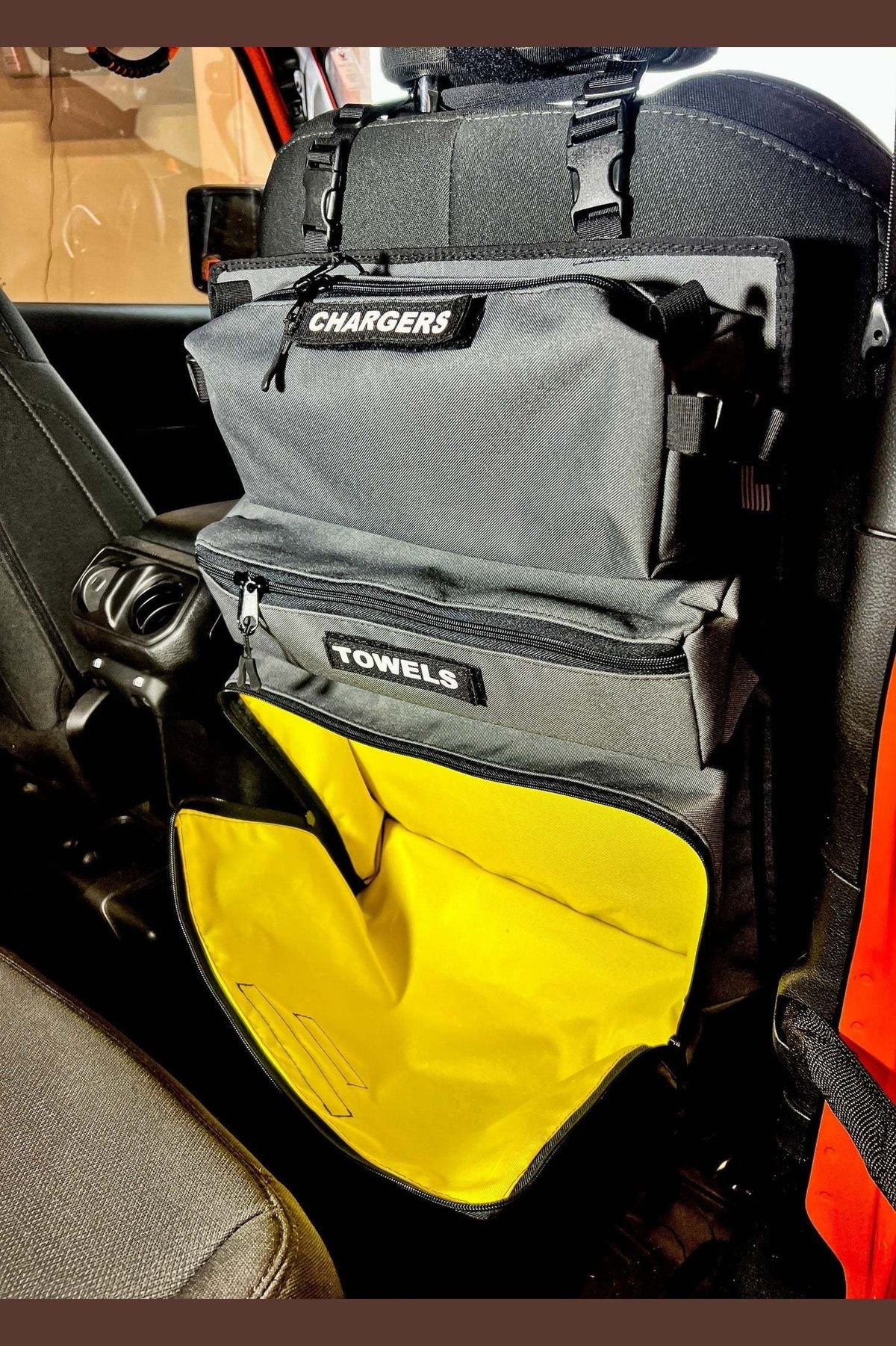 Car seat back with Arches Overlander 1 Seat Organizer featuring labeled storage compartments in a vehicle.