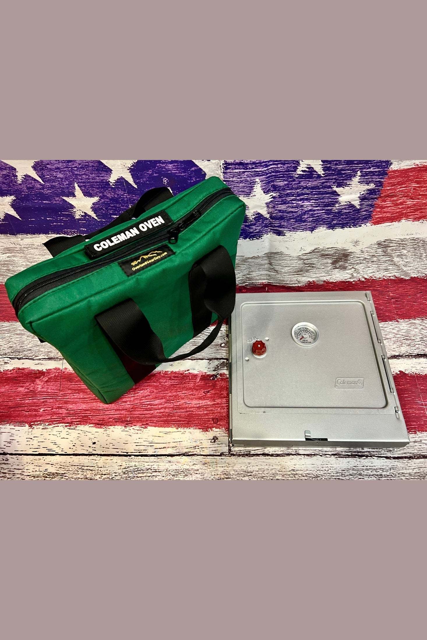 Green Coleman Rugged Oven padded carry bag with durable handles next to a silver Coleman oven on an American flag background