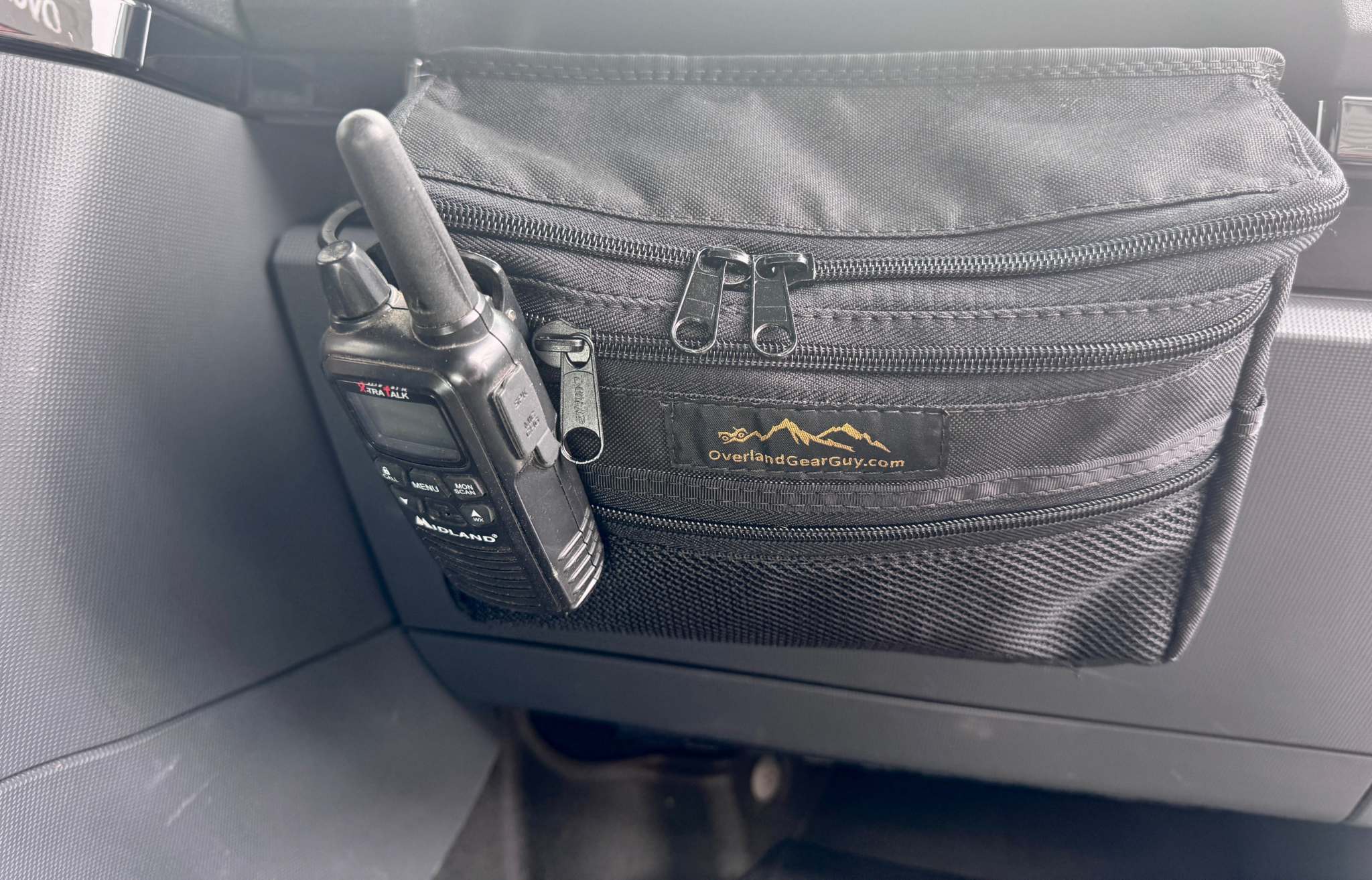 Grenadier Grab Handle Storage Bag attached to vehicle grab bar with multiple zippered pockets and walkie-talkie holder
