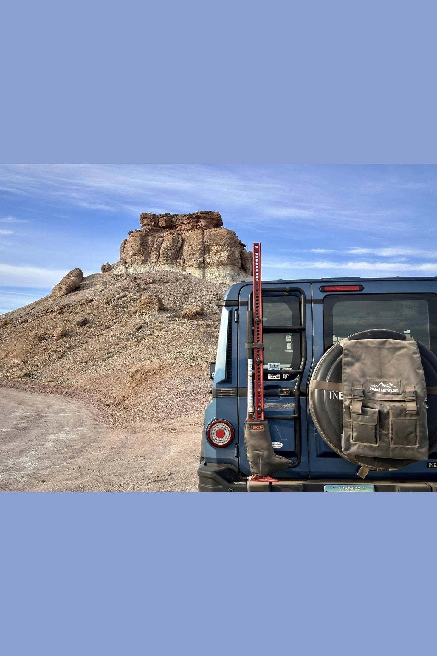 Spare tire trash bag mounted on SUV in desert landscape.