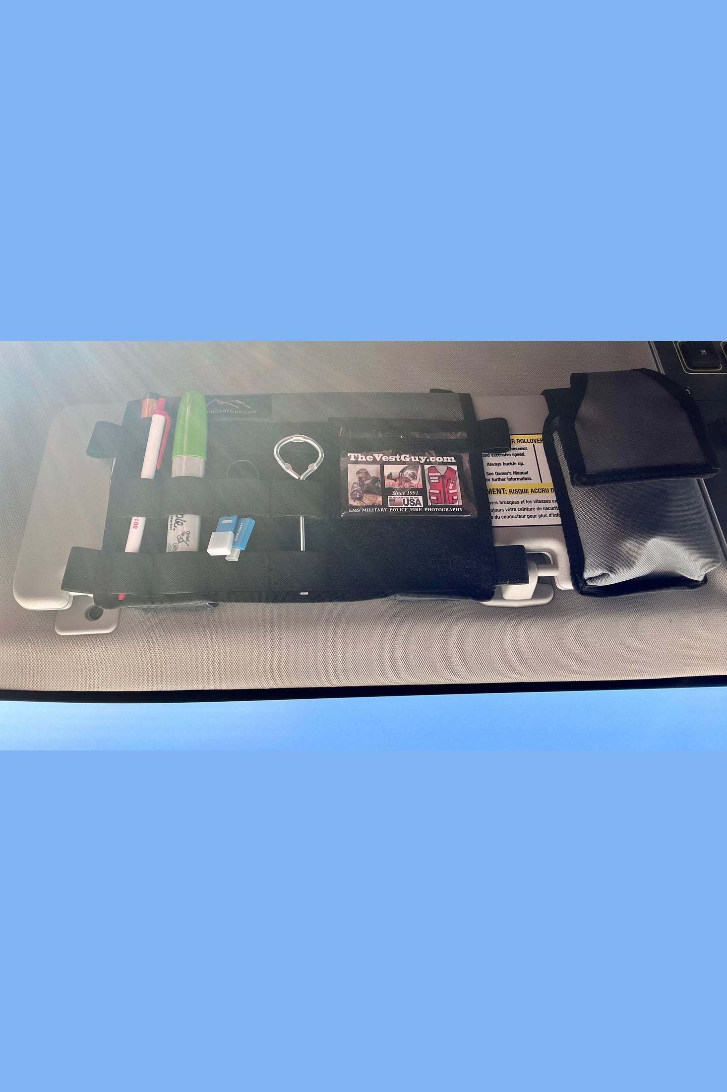 INEOS Grenadier MOLLE Visor Organizer with multiple compartments attached to a sun visor, holding pens and small items.