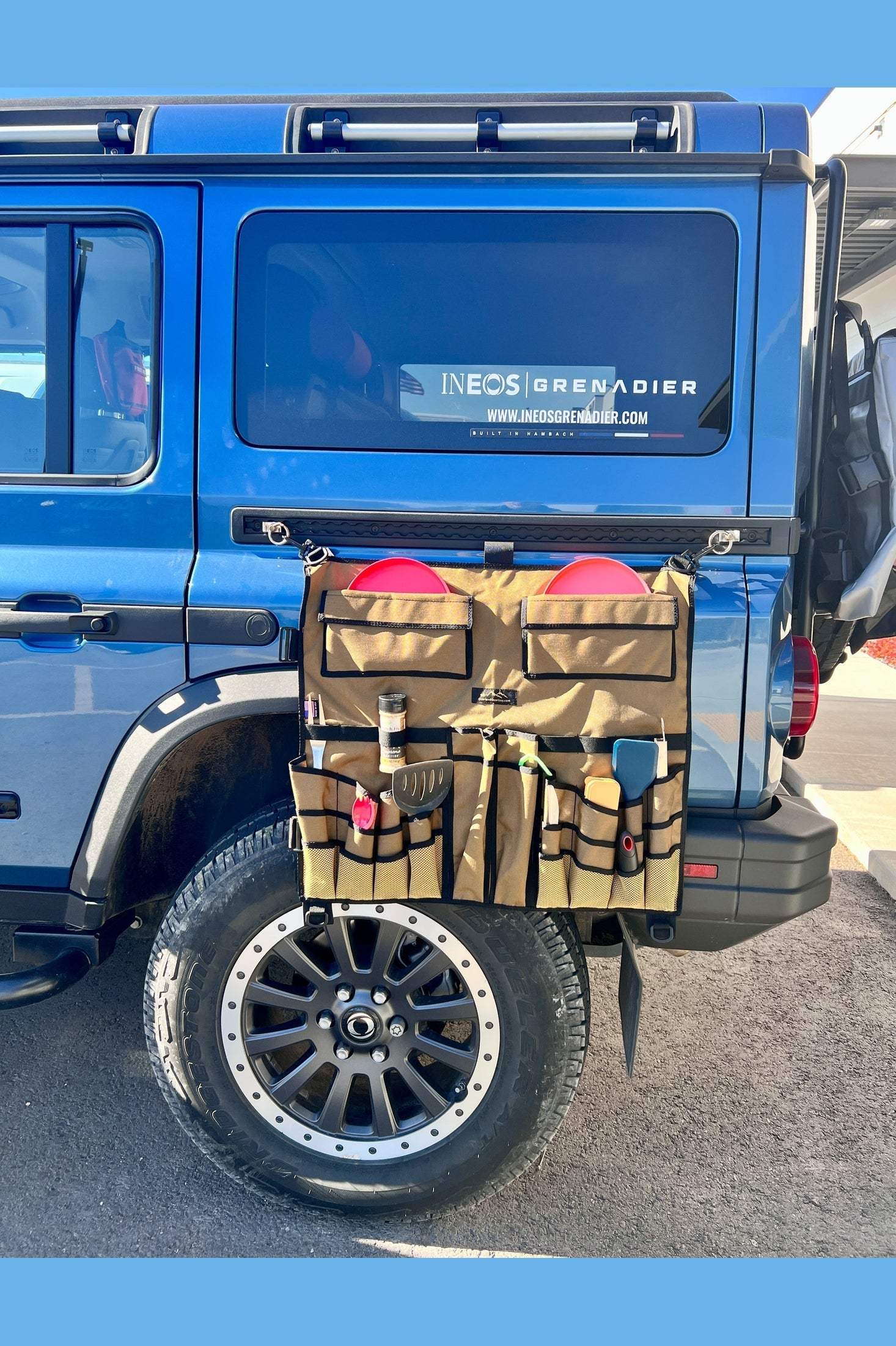 INEOS Grenadier Overlander Utensil Organizer mounted on blue vehicle with camping utensils and tools neatly stored.