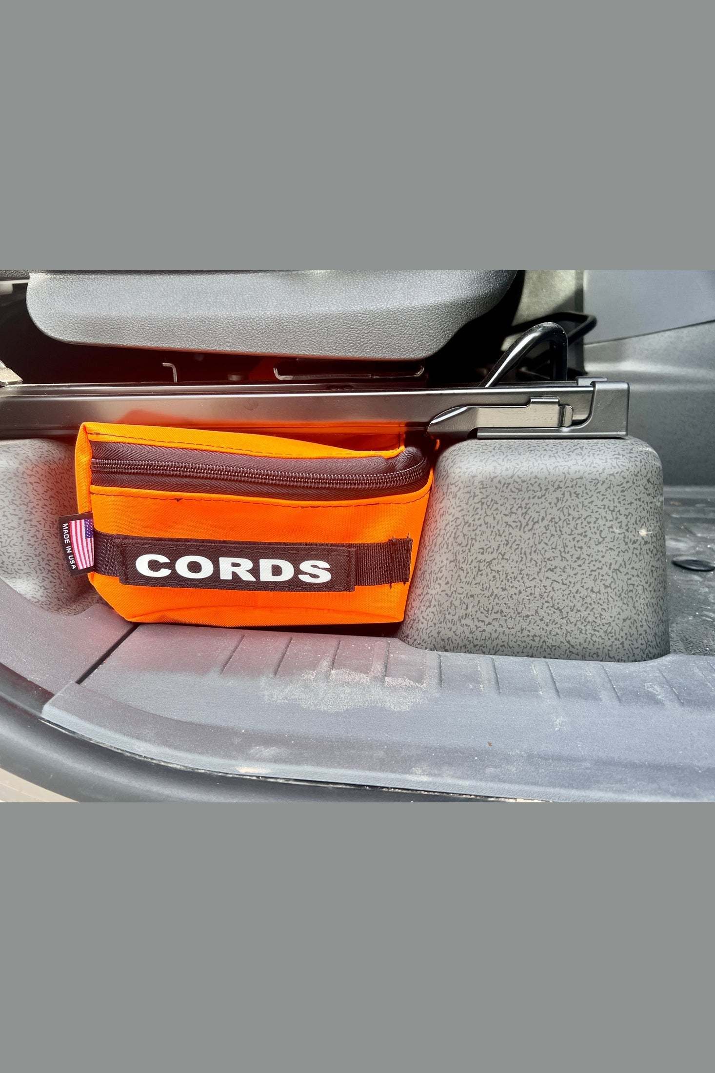INEOS Grenadier under seat storage bag in orange for organizing cords and small tools in vehicle interior