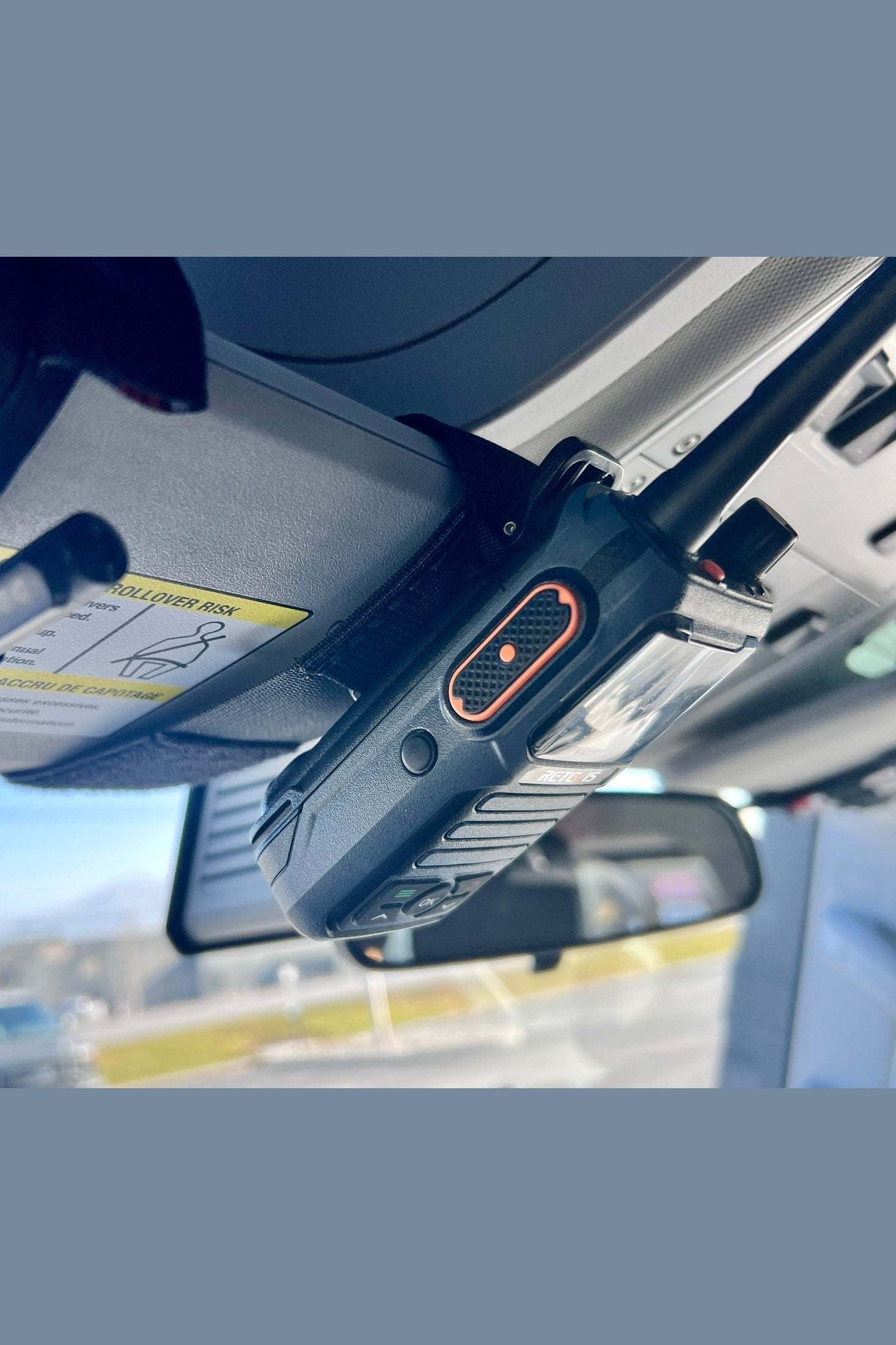 Sun Visor Radio Pouch holding a radio clipped onto a sun visor in a vehicle interior.