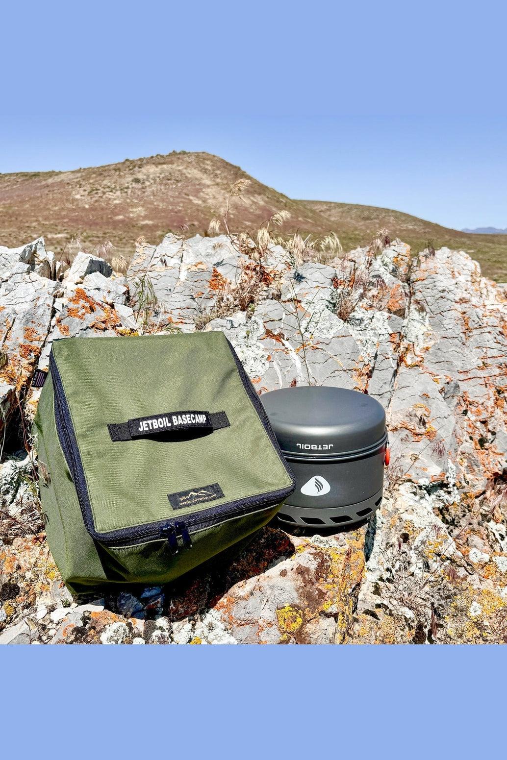 Genesis Basecamp Carrying Bag in olive drab green with Jetboil camping stove on rocky outdoor terrain