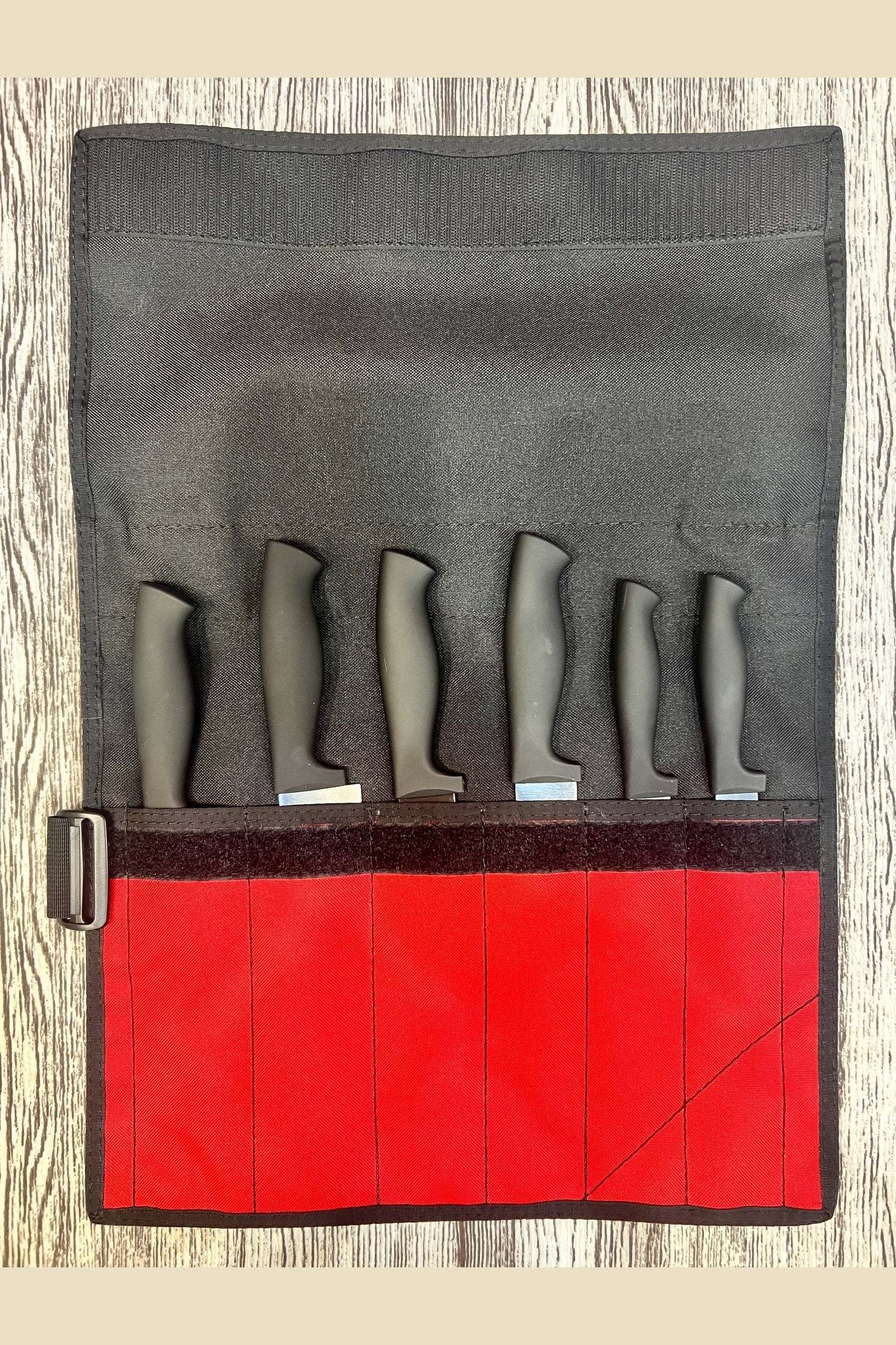 Compact black and red knife roll holding six knives with secure velcro closure