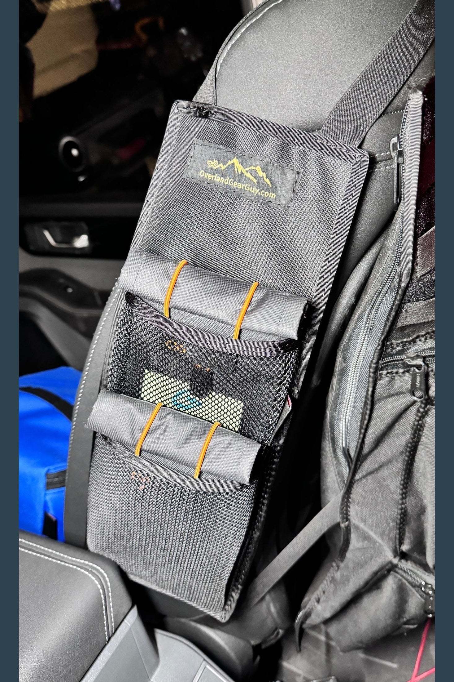 Black mesh mini seat organizer attached to car seat with multiple compartments for small items storage