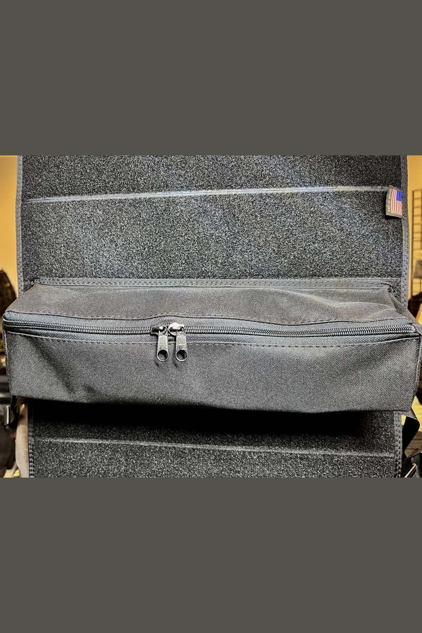 Modular Velcro poplar pocket organizer with zipper, attached to carpeted surface, black color