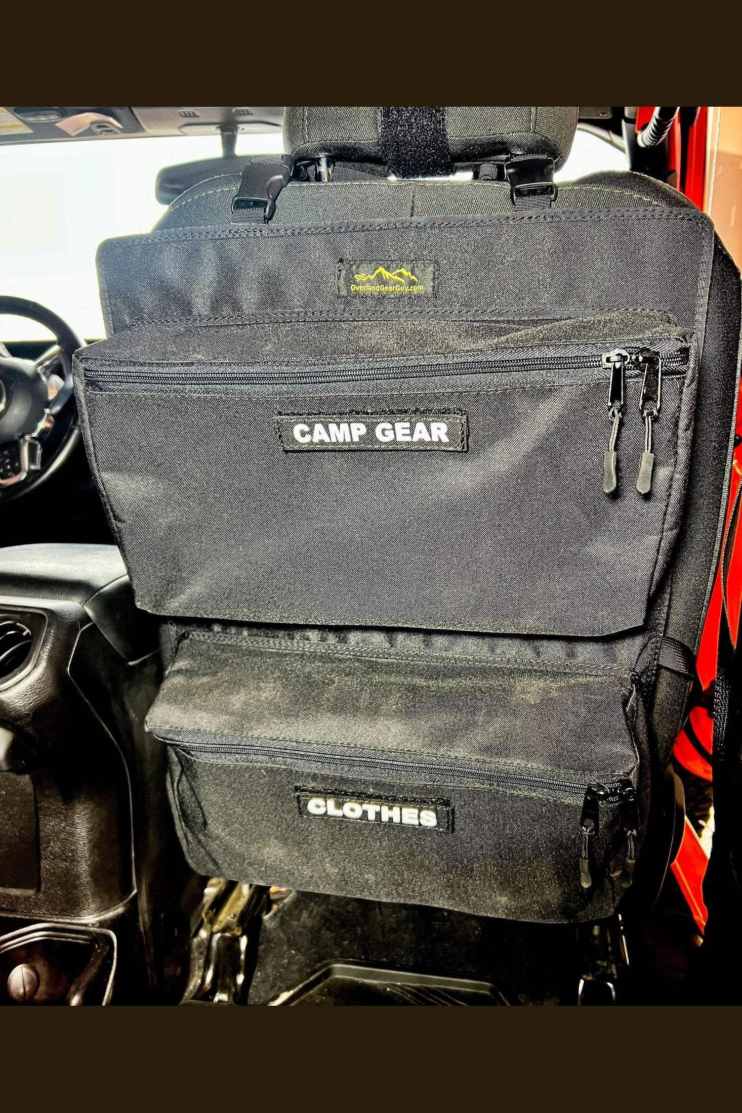 Overlander 2 Seat Organizer hanging on vehicle seat with labeled storage compartments for camp gear and clothes