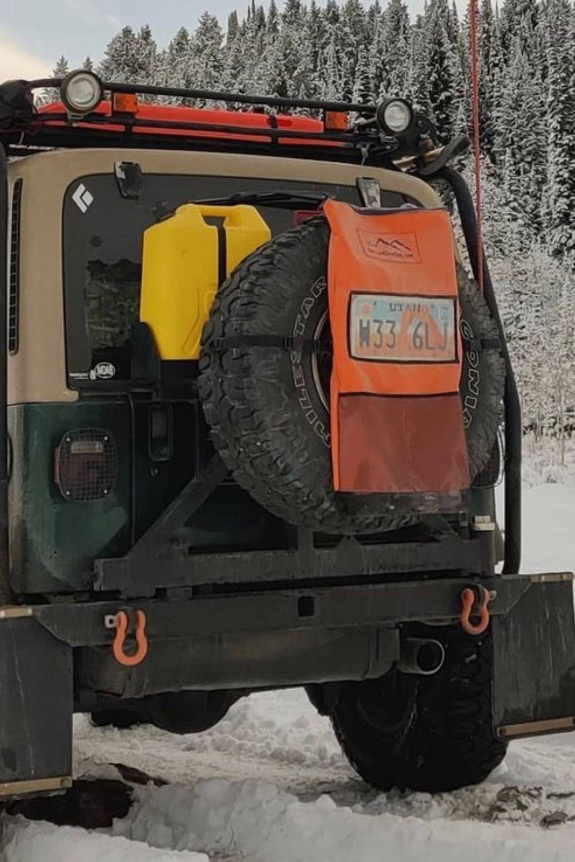 Pack It Out Bag II mounted on vehicle spare tire with license plate holder in snowy outdoor setting