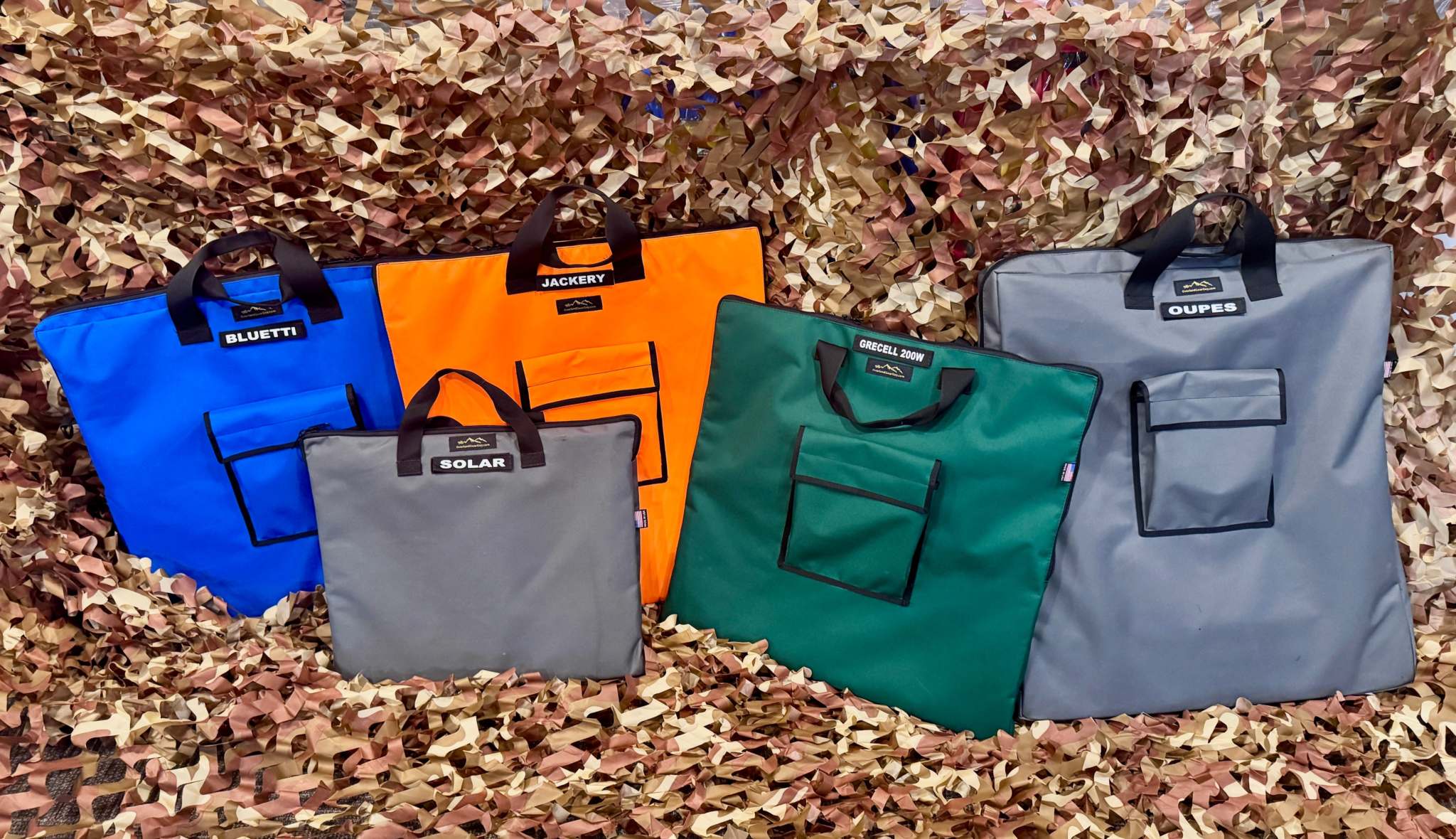 Colorful durable solar panel carry bags with front pockets and Velcro ID tags for various brands, displayed on camouflage background