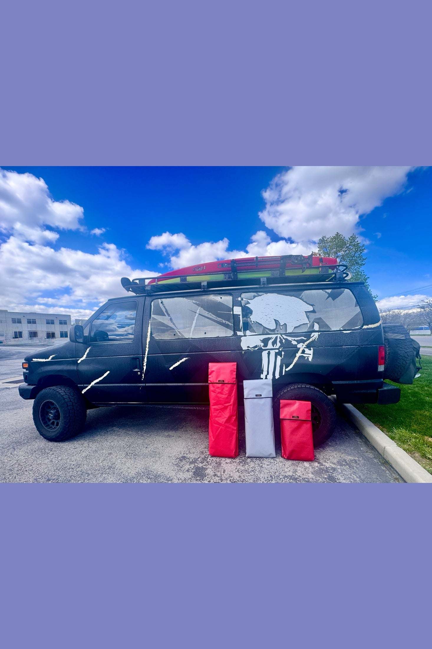 Durable traction recovery board storage bags in red and gray next to black off-road van with roof rack carrying recovery boards