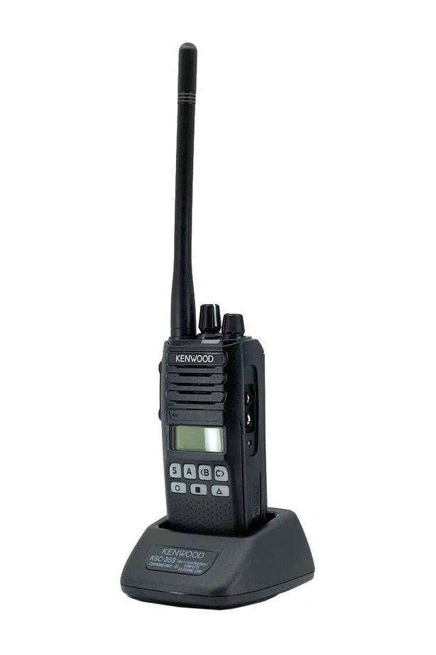 Kenwood NX-1300 UHF handheld radio on charging dock with alphanumeric display.