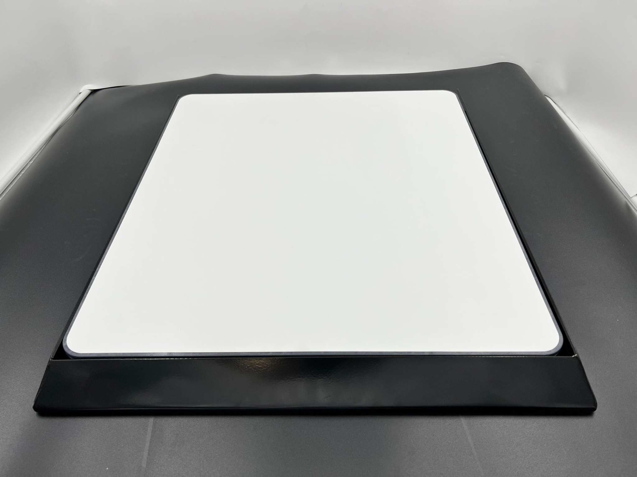 Black car hood with a white square patch on a gray background