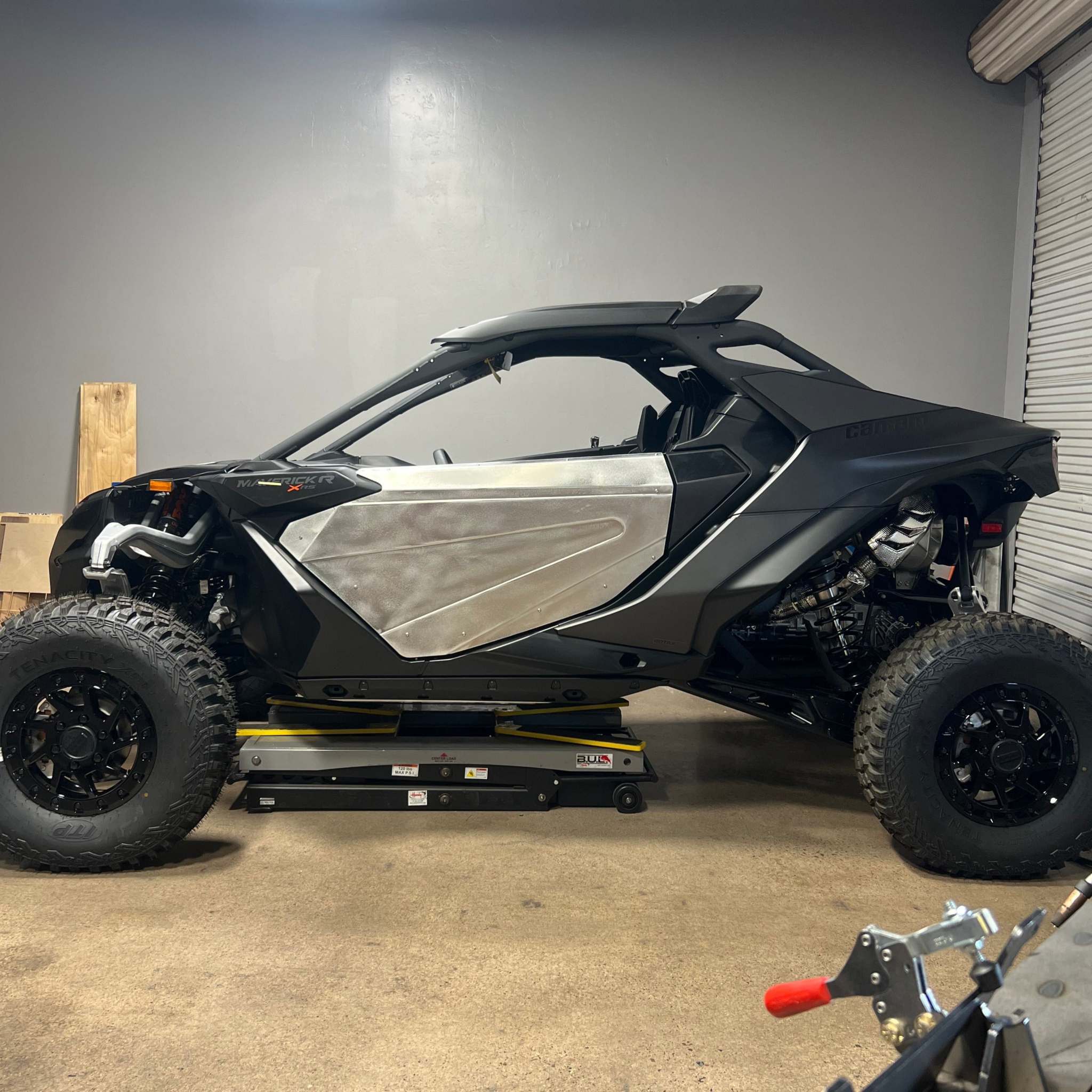 Off-road vehicle equipped with black and silver TMW Maverick R doors in a garage setting