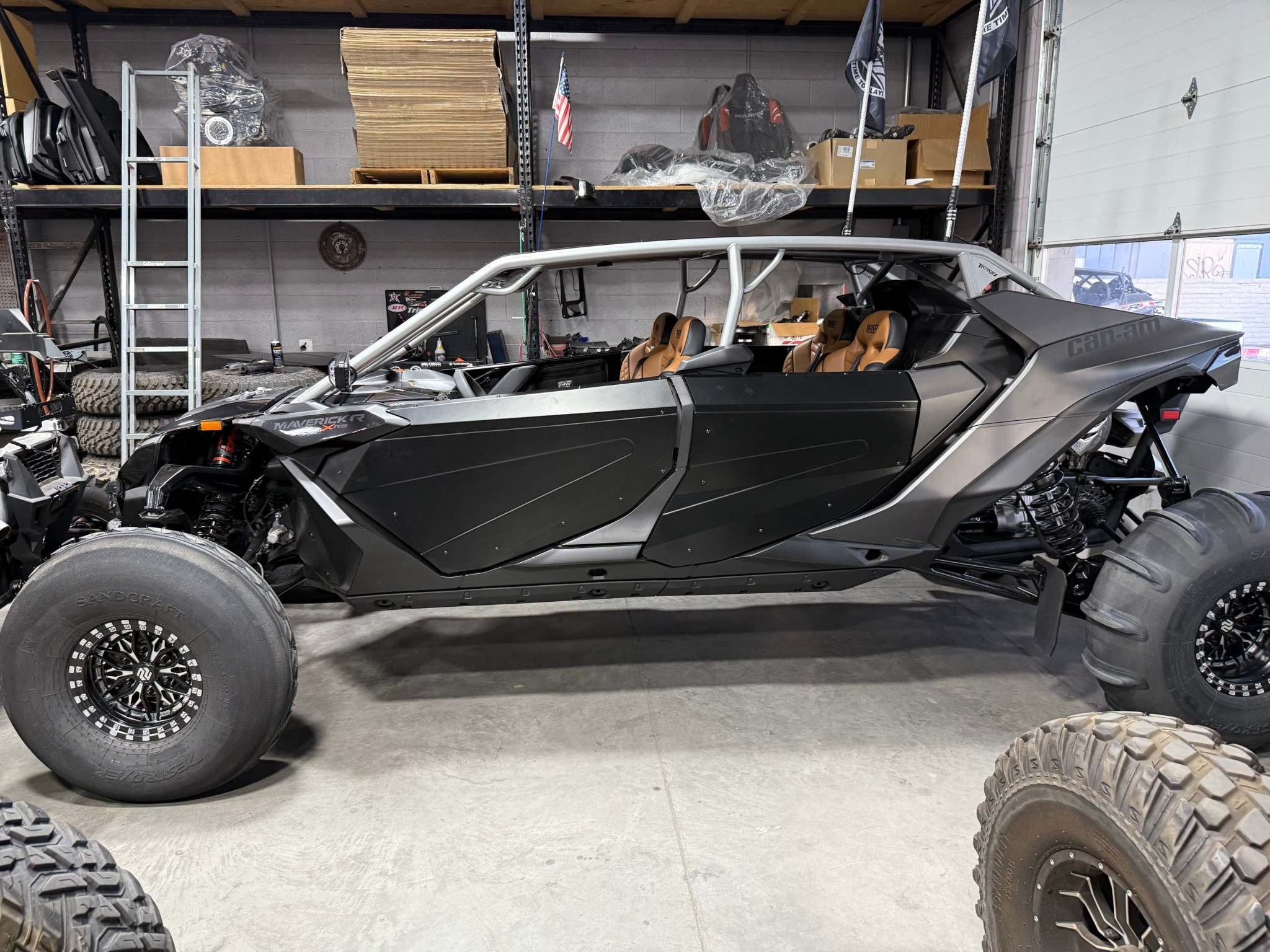 Side view of a Can-Am Maverick equipped with black TMW Maverick R Max doors in a garage setting