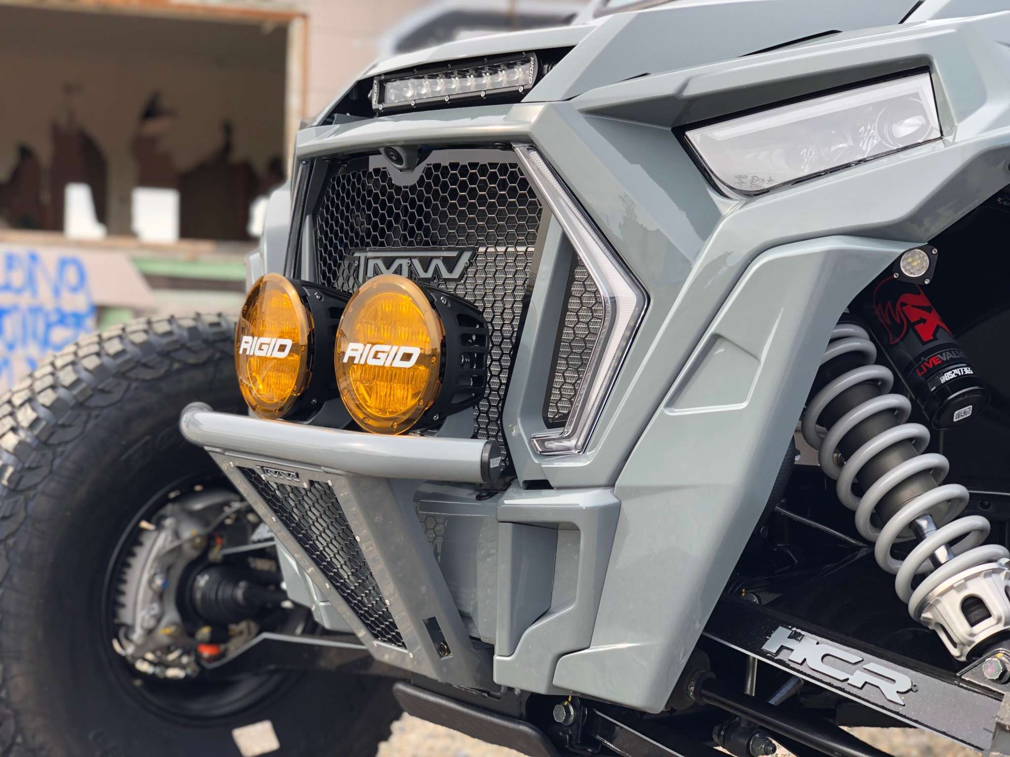 Close-up of rugged offroad vehicle front featuring TMW xp turbo s grill with mesh design and dual yellow Rigid lights