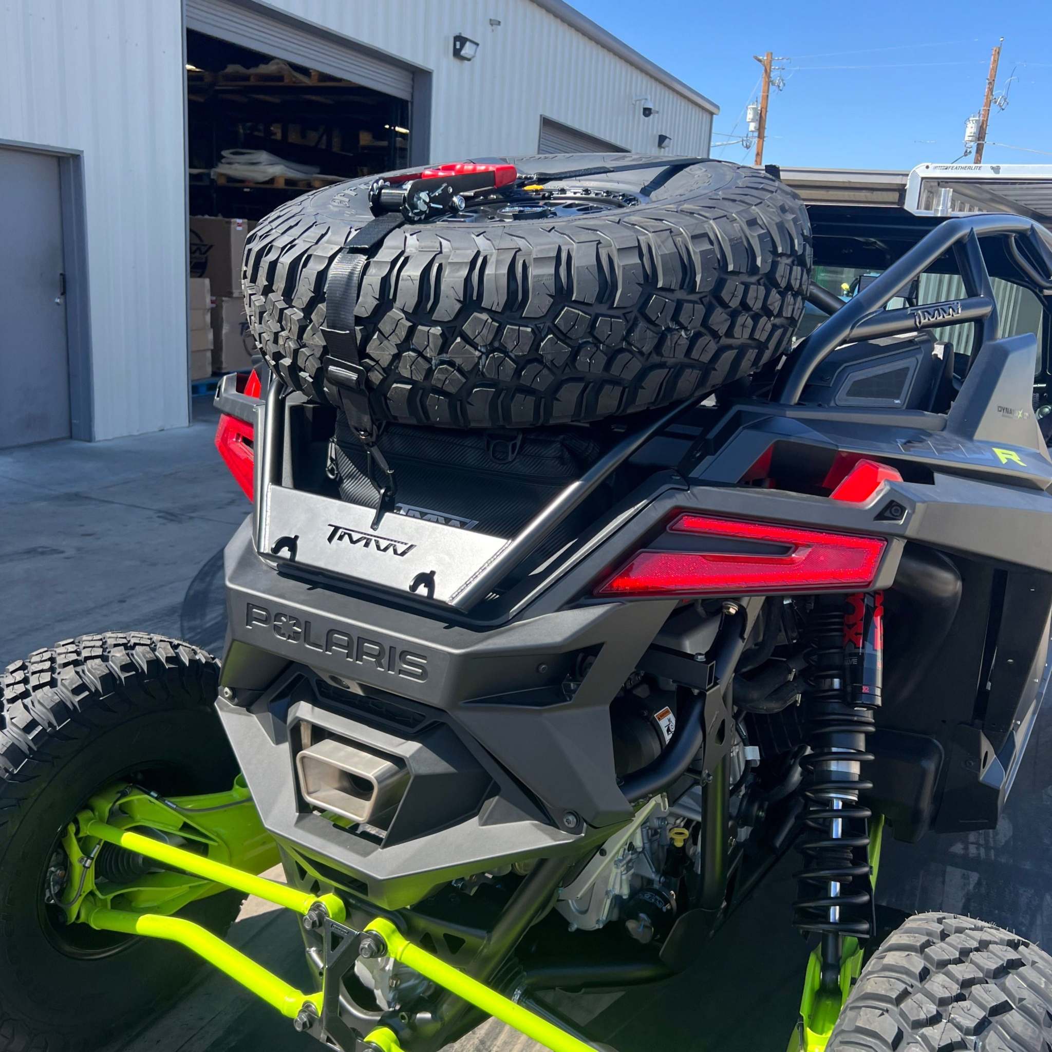 TMW RZR PRO Spare Tire Rack mounted on Polaris RZR with secured large spare tire and heavy-duty strap