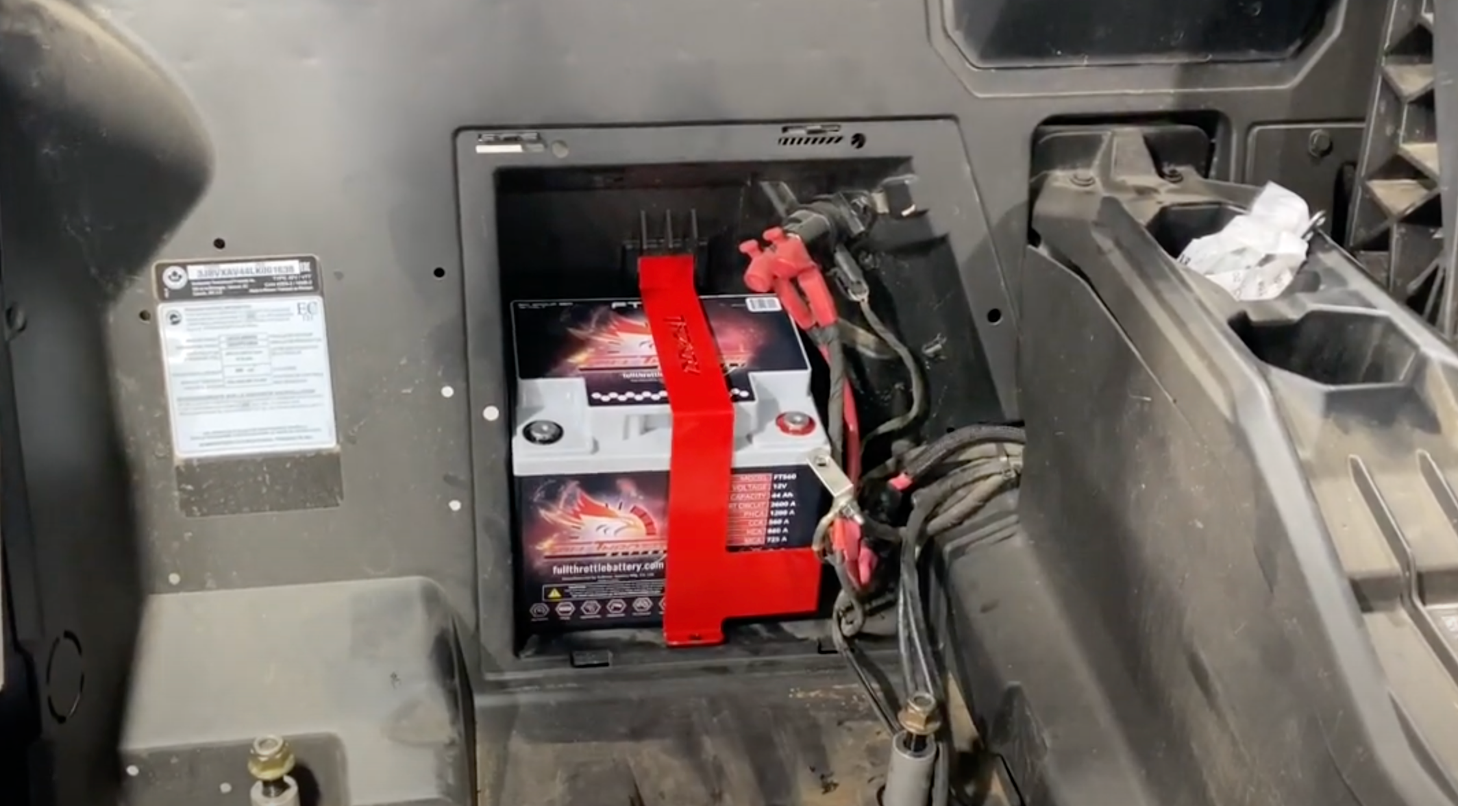 Red TMW X3 Battery Strap securing a battery inside a Can Am X3 vehicle compartment