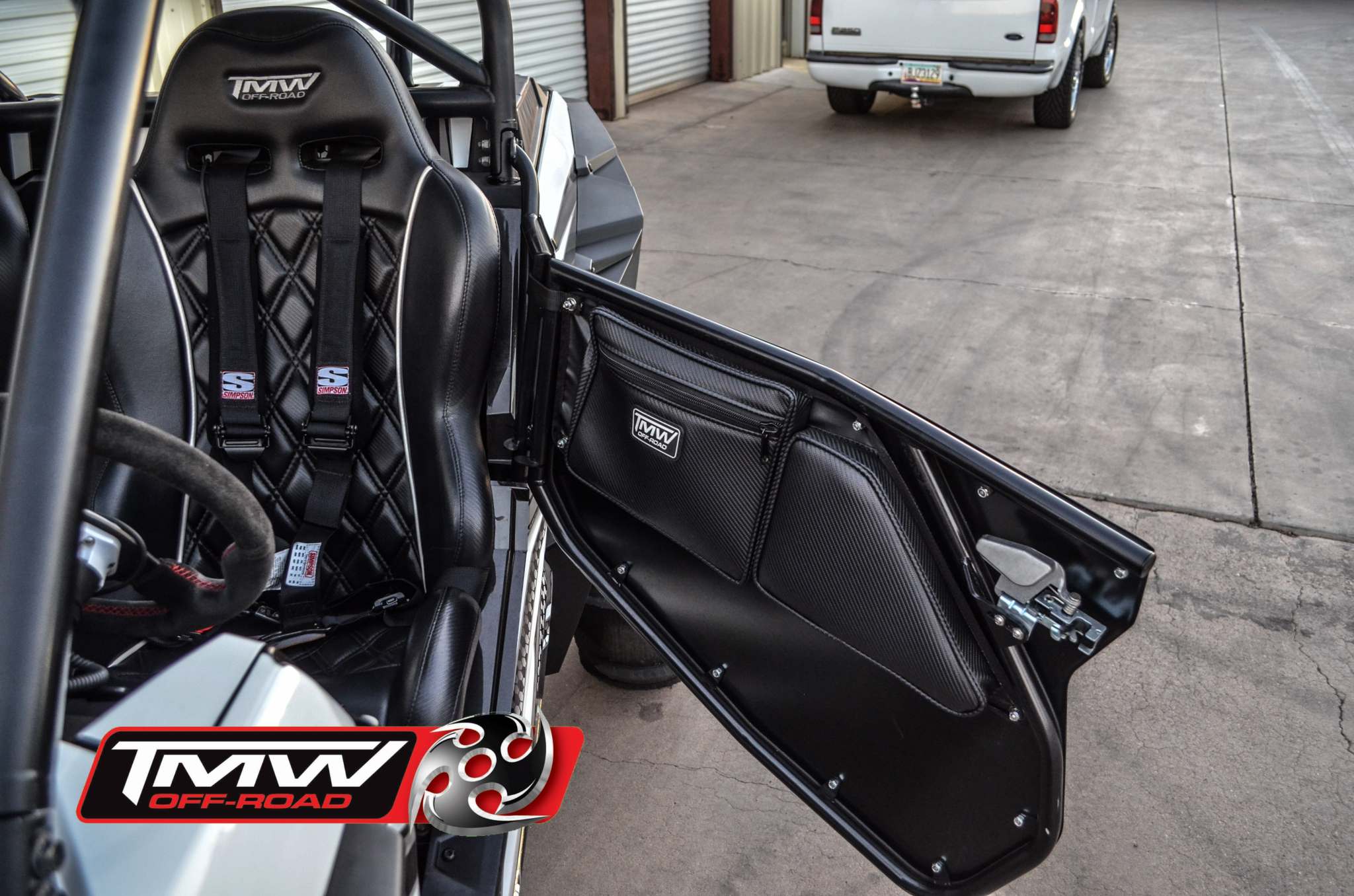 TMW 2 Seat RZR carbon fiber pattern door bag with storage pocket and leg rest pad installed on off-road vehicle door.