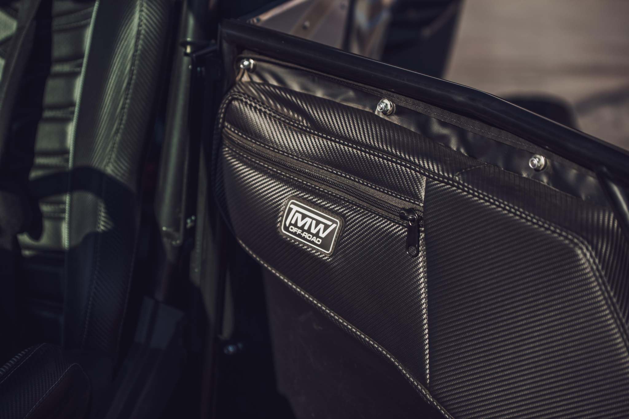 TMW 4 Seat RZR Door Bags with carbon fiber pattern and storage pocket mounted on sidewinder 4 seat doors for comfort and convenience