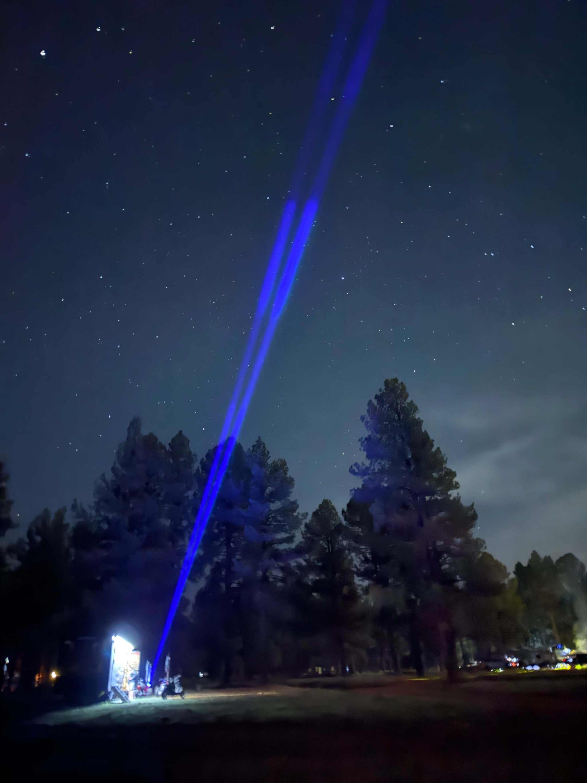 RGB Lunar Laser Whips Kit projecting bright blue laser beams into the night sky over a forested area